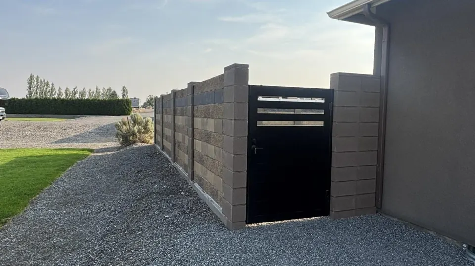 Ornamental iron gate set in a brown block fence